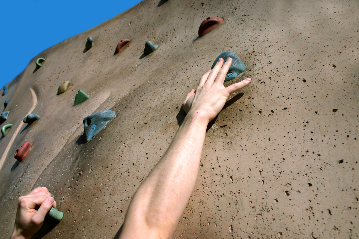 Reaching for handhold on climbing wall, representing hope, effort, and change
