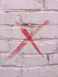 Red x painted on brick wall