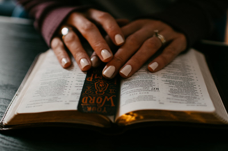 Bible with woman's hands reading and bookmark