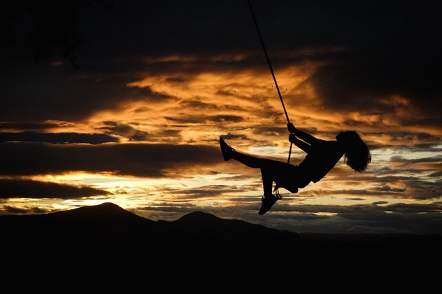 Woman on swing in the sunset