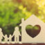 Family holding hands by wooden home with heart on it